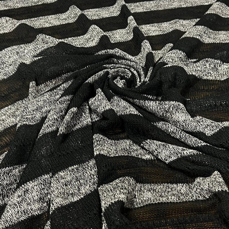Striped sweater knit fabric featuring heather grey and sheer black swiled into a pile to show off soft drape