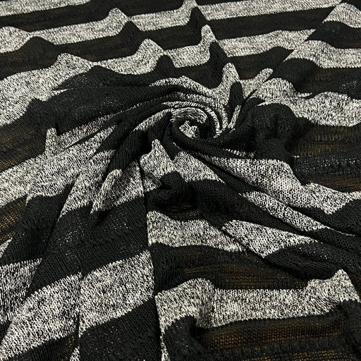 Striped sweater knit fabric featuring heather grey and sheer black swiled into a pile to show off soft drape