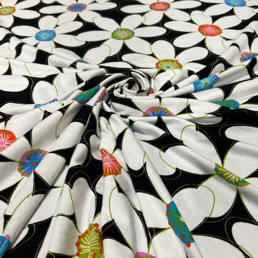 Cotton jersey knit fabric with large format floral print on black background. 
