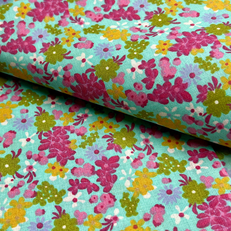 Floral fabric with pink, green, and yellow flowers on a teal background