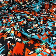 Colorful fabric with abstract pattern in orange, blue, black, and white.