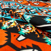 Close-up of fabric with a colorful pattern featuring animals and geometric shapes.