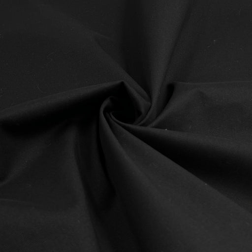 Closeup of black cotton/lycra stretch twill fabric folded into a swirl. This material displays 20% stretch widthwise, and is ideal for fitted suits, jackets, trousers, and more. 