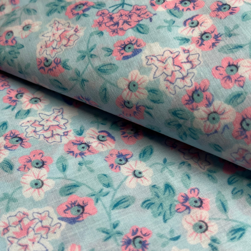Floral fabric pattern with pink and purple flowers on a light blue background