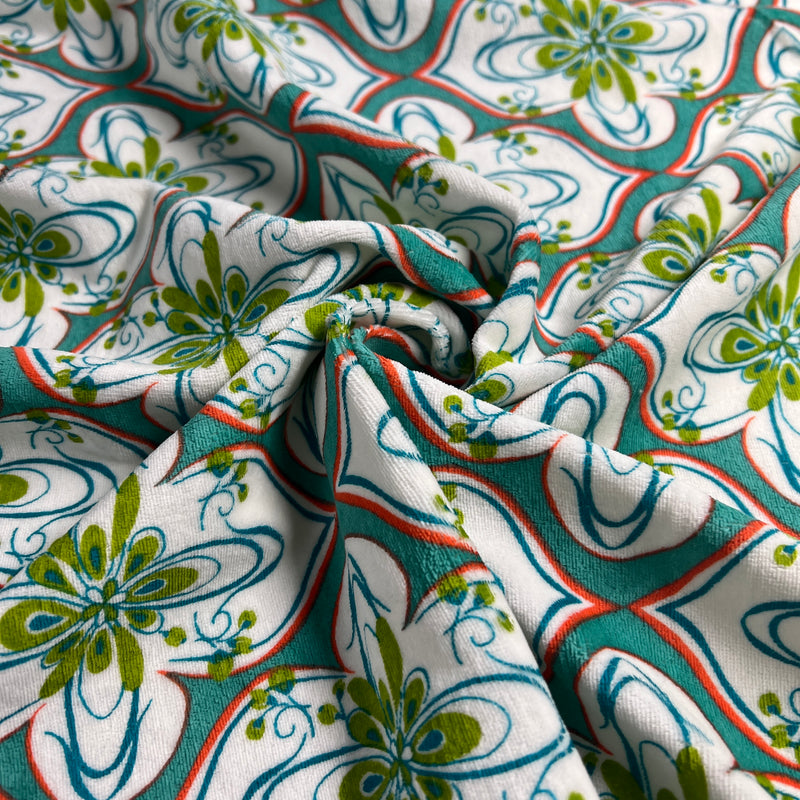 Close-up of patterned fabric with green, blue, and red design on white background