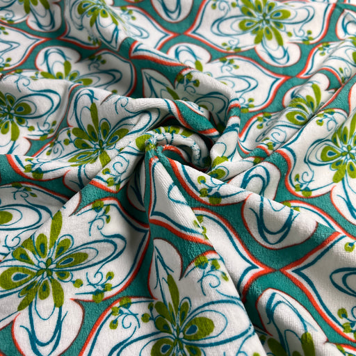 Close-up of patterned fabric with green, blue, and red design on white background