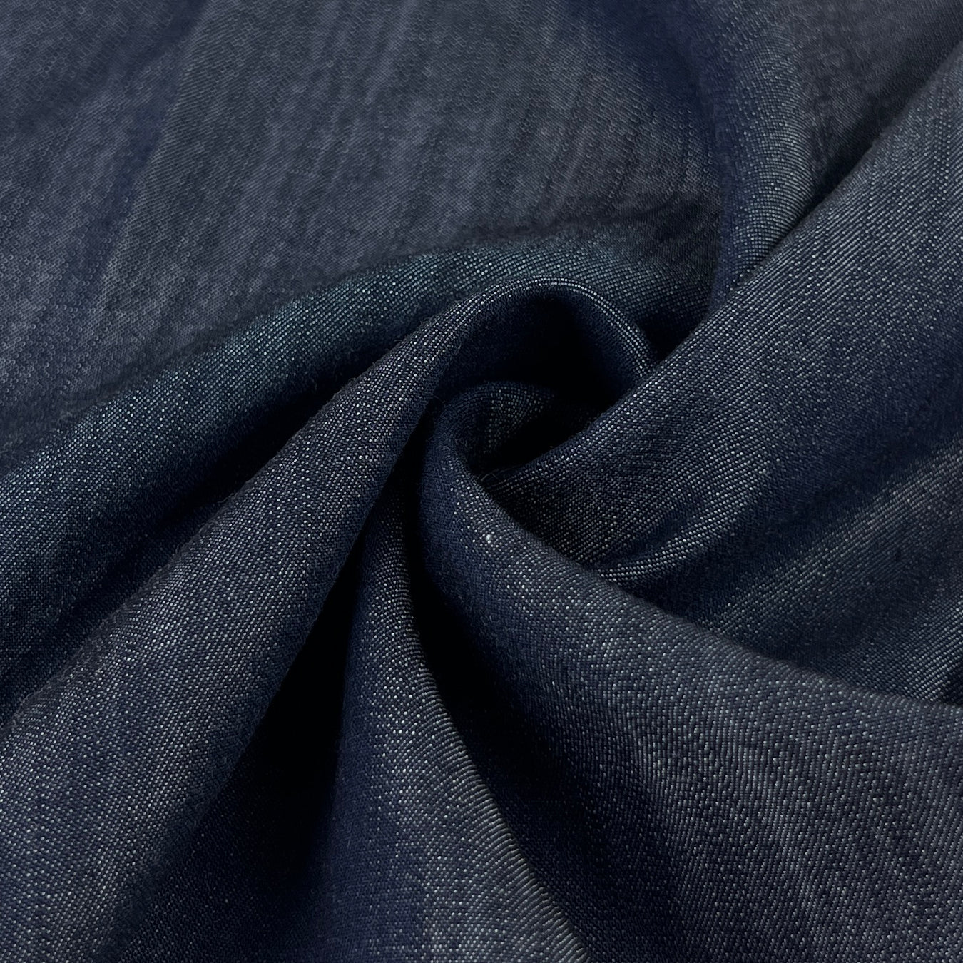 Close-up of dark indigo 100% tencel denim fabric with a subtle sheen