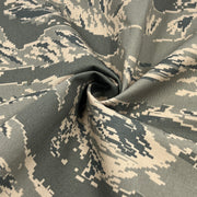 Digital camouflage fabric with a pixelated pattern in shades of gray and beige.