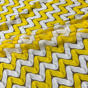 yellow and white zig zag crochet fabric piled on a table