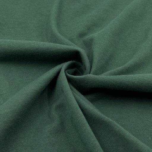 Closeup of hunter green cotton jersey pulled into a swirl to show off softness and drape. 