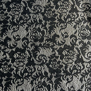 Black floral lace pattern on a textured fabric background