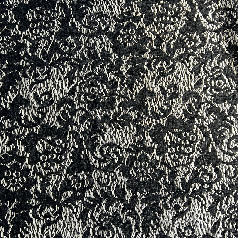Black floral lace pattern on a textured fabric background