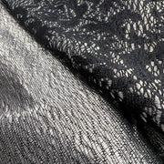Close-up of black lace fabric with a subtle pattern on a plain background