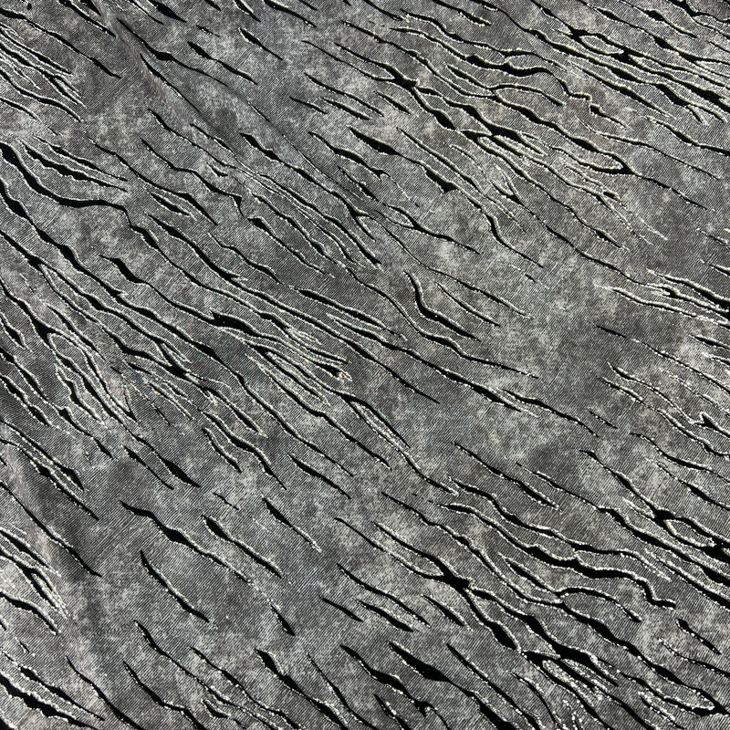 Grey fabric with slate like pattern, textured with flocked zebra stripes which are outlined in glitter