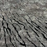 Grey fabric with slate like pattern, textured with flocked zebra stripes which are outlined in glitter