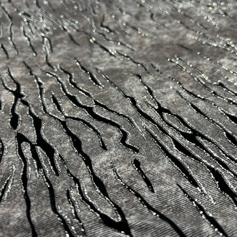 Grey fabric with slate like pattern, textured with flocked zebra stripes which are outlined in glitter