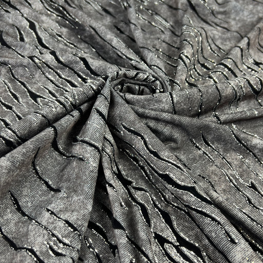 Grey fabric with slate like pattern, textured with flocked zebra stripes which are outlined in glitter