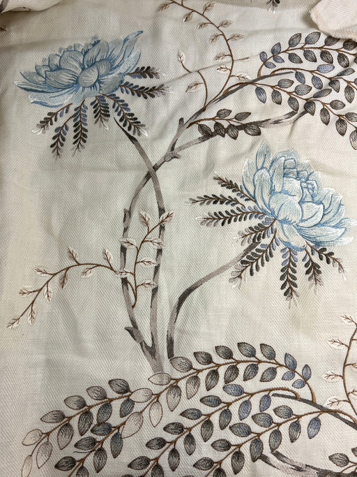 Embroidered fabric with blue flowers and branches on a white background
