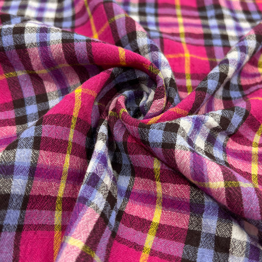 Close-up of plaid fabric with pink, purple, and yellow colors pulled into a swirl to show off lightweight body and drape.