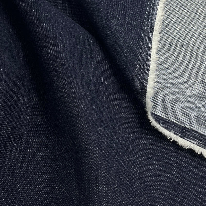 Close-up of a folded dark navy fabric with a lighter gray-blue reverse side and frayed edge.