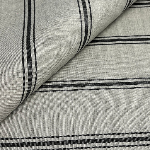 A close-up of woven fabric with a light gray base and black horizontal stripes, shown with one corner folded over to reveal the texture.