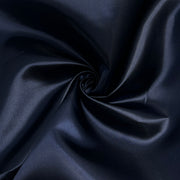A close-up of dark navy blue satin fabric arranged in a spiral swirl, showing its smooth texture and subtle sheen.