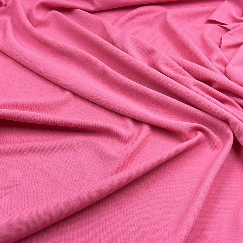 A close-up of draped pink fabric with soft folds and a smooth texture filling the frame.