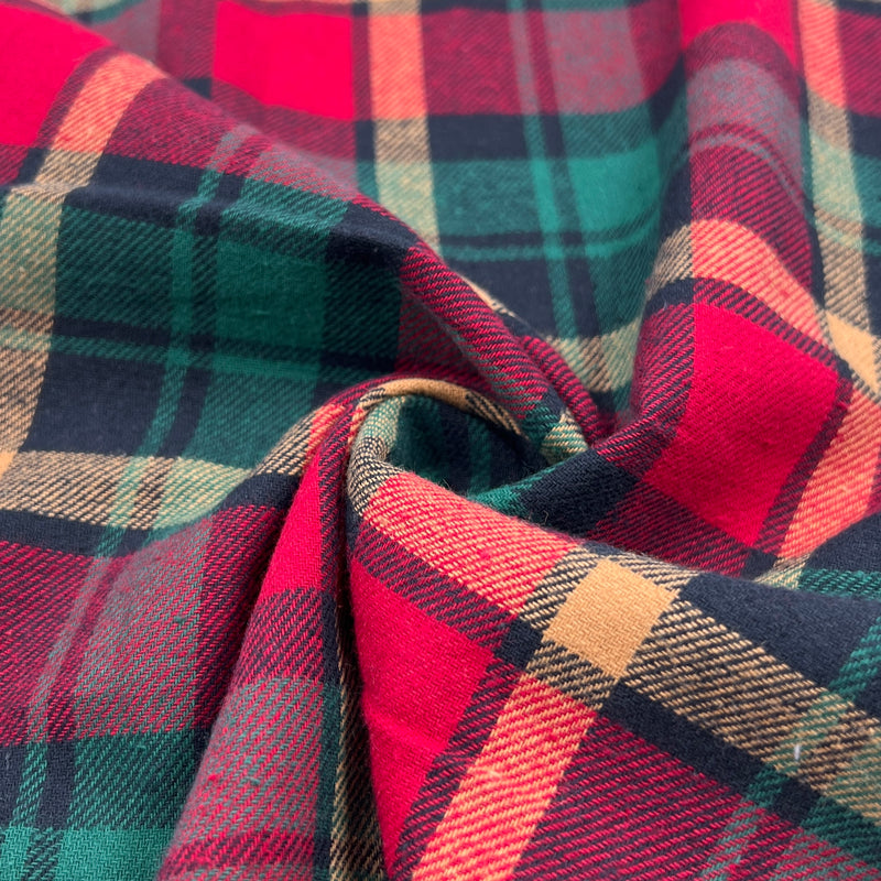 Lightweight flannel shirting fabric featuring a classic woven plaid design using christmas colors of green, red and gold. 