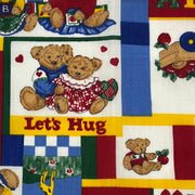 Colorful fabric with teddy bears and text 'Let's Hug' on a patchwork pattern.