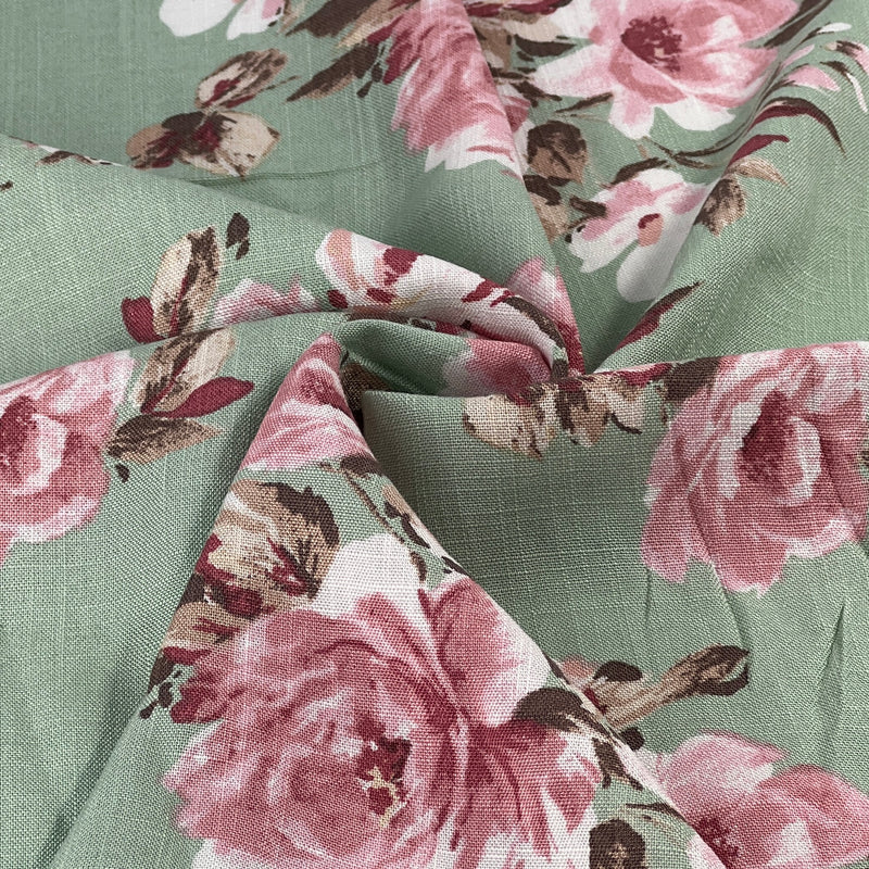 Floral rayon dress weight fabric with pink roses on a green background
