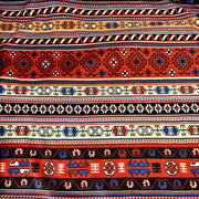 Patterned fabric with tribal design in red, blue, and beige on a white background