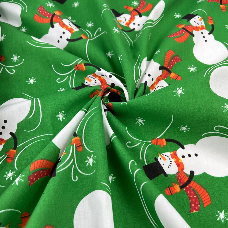 Green fabric with snowman pattern on a green background