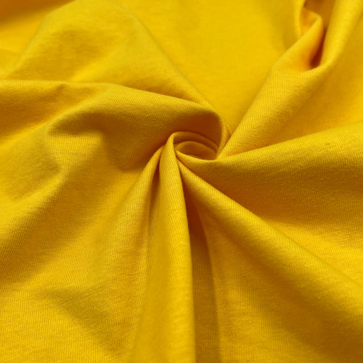 Closeup of 100% cotton jersey in vibrant yellow color pulled into a swirl. 
