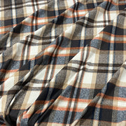 A close-up of draped plaid fabric with a pattern of navy blue, charcoal gray, beige, and rust orange stripes.