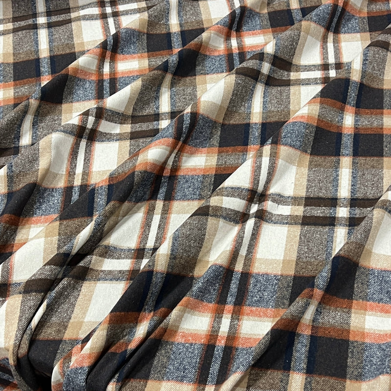 A close-up of draped plaid fabric with a pattern of navy blue, charcoal gray, beige, and rust orange stripes.