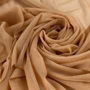 A close-up of draped champagne beige fabric with a subtle shimmering texture, arranged in a spiral pattern.