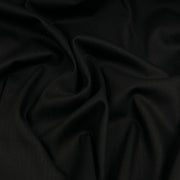 A close-up of draped black fabric with soft folds and a smooth texture.