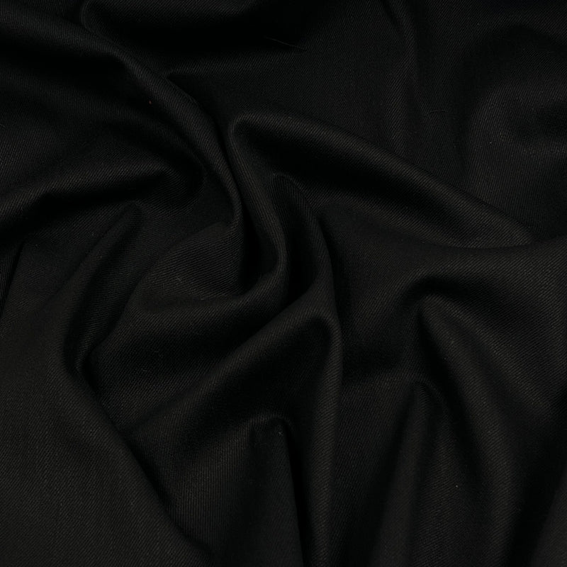 A close-up of draped black fabric with soft folds and a smooth texture.