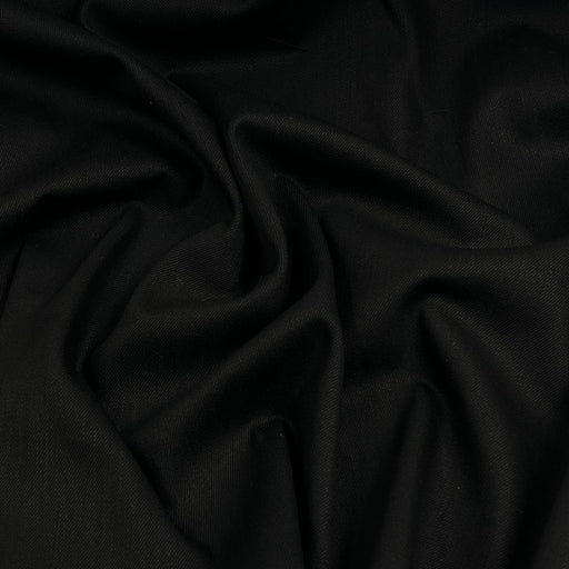 A close-up of draped black fabric with soft folds and a smooth texture.