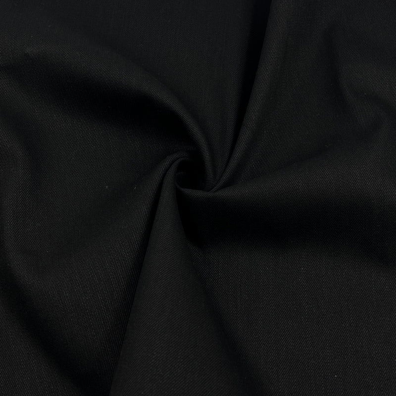 A close-up of black fabric with a gathered swirl in the center, showing the material texture and drape.