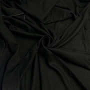 Black fabric draped in soft folds, showing a smooth matte texture with a gathered swirl in the center.