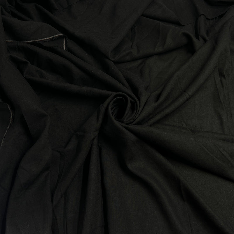 Black fabric draped in soft folds, showing a smooth matte texture with a gathered swirl in the center.