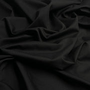 Closeup of black twill fabric bunched into a pile, showing off diagonal ridged texture. 