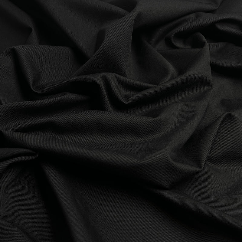 Closeup of black twill fabric bunched into a pile, showing off diagonal ridged texture. 