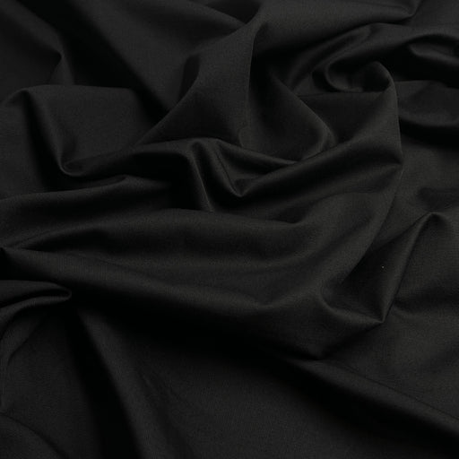 Closeup of black twill fabric bunched into a pile, showing off diagonal ridged texture. 