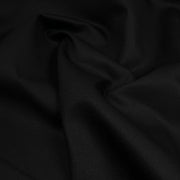 A close-up of draped black fabric with soft folds and a subtle woven texture.