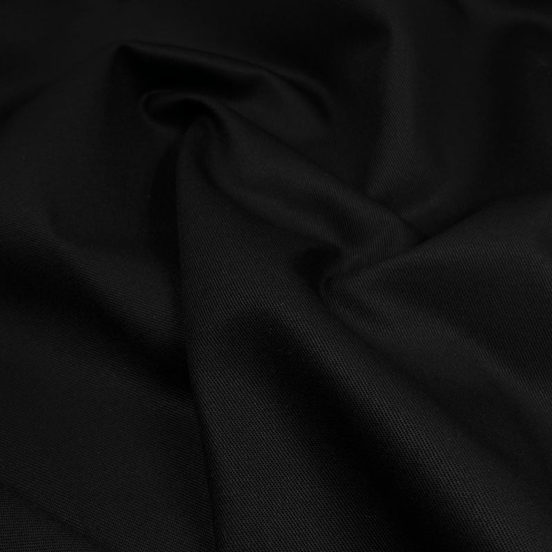 A close-up of draped black fabric with soft folds and a subtle woven texture.
