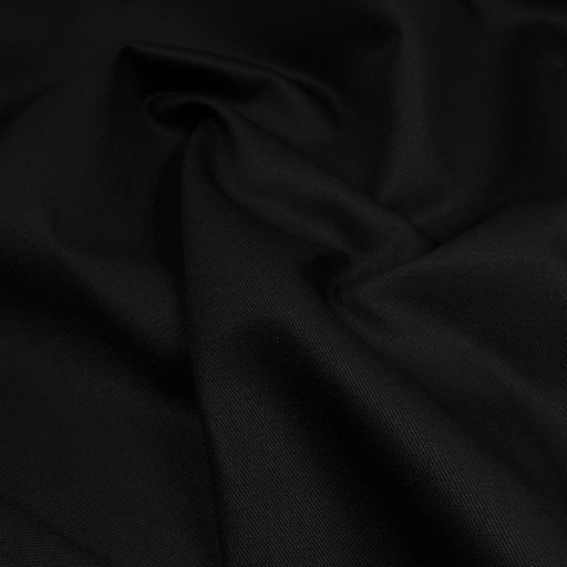 A close-up of draped black fabric with soft folds and a subtle woven texture.