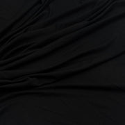 A close-up of draped black fabric with soft folds and a smooth texture.