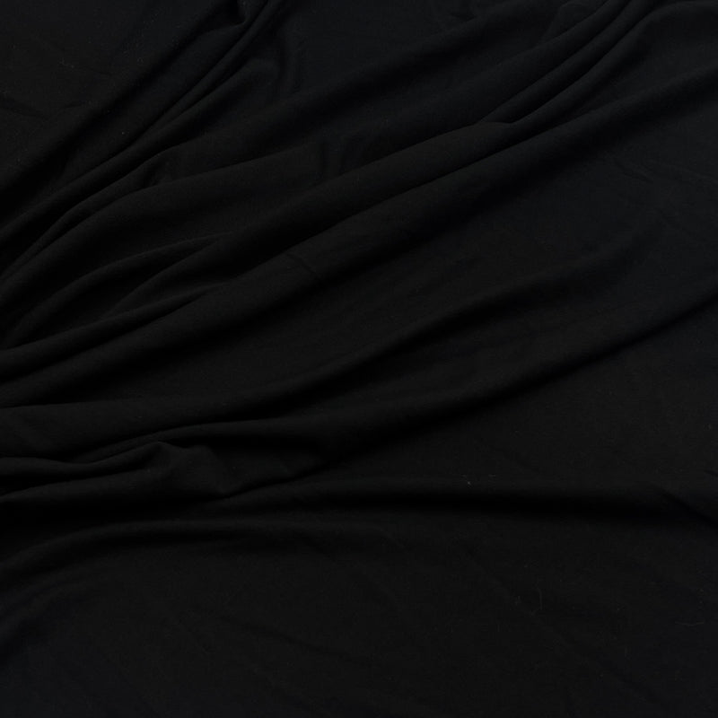 A close-up of draped black fabric with soft folds and a smooth texture.
